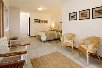 a bedroom with a bed and two chairs at Pacem cottage in Hermanus