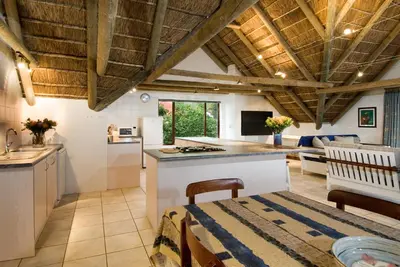 a kitchen and living room with wooden ceilings at Pacem cottage in Hermanus