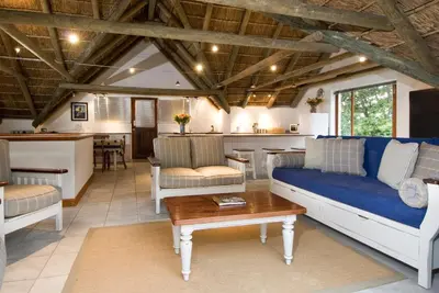 a living room with a blue couch and a table at Pacem cottage in Hermanus
