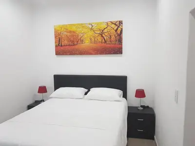 a bedroom with a white bed and a painting on the wall at Fama Lodge Rm13 in Cape Town