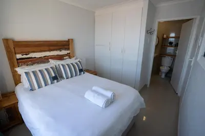 a bedroom with a white bed with towels on it at Nothing But View in Hermanus