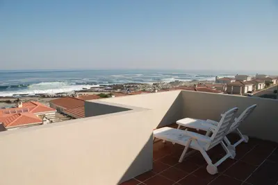 a white chair sitting on a balcony overlooking the ocean at Nothing But View in Hermanus