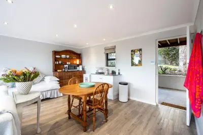 a kitchen and living room with a table and chairs at Protea & Pincushion Cottages in Hermanus