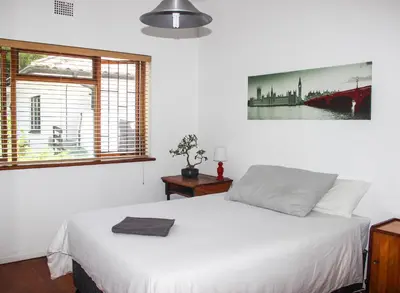 a bedroom with a white bed and a window at Norfolkden Beachhouse in Hermanus