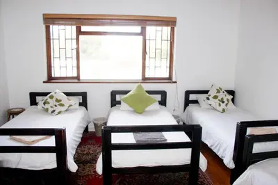 a room with three beds and two chairs and a window at Norfolkden Beachhouse in Hermanus
