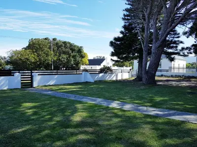 a yard with a white fence and a tree at Norfolkden Beachhouse in Hermanus