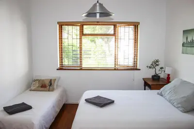 two beds in a room with a window at Norfolkden Beachhouse in Hermanus