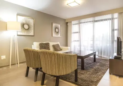 a living room with a table and a couch at Modern 2 bedroom with underground parking 1 mins from beach-205 La Cabina, Blouberg, Cape Town in Bloubergstrand
