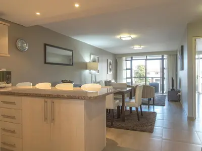 a kitchen with a table and a dining room at Modern 2 bedroom with underground parking 1 mins from beach-205 La Cabina, Blouberg, Cape Town in Bloubergstrand