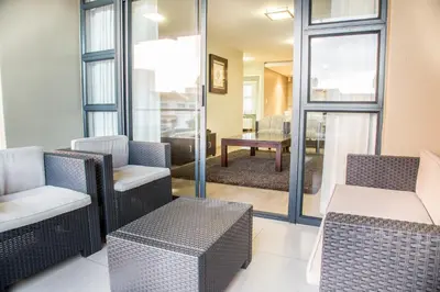 a living room with chairs and a table at Modern 2 bedroom with underground parking 1 mins from beach-205 La Cabina, Blouberg, Cape Town in Bloubergstrand
