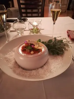 a plate with a dessert on a table with wine glasses at A310 Lagoon Beach Apartment & Spa in Cape Town