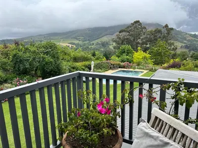 a balcony with a bench and flowers and a pool at Camberley Wines - Luxury Accommodation in Stellenbosch