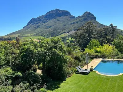 a swimming pool in a yard with mountains in the background at Camberley Wines - Luxury Accommodation in Stellenbosch