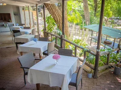 two tables and chairs with white tables and flowers on a patio at Picardie Guest Farm in Paarl