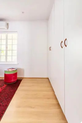 a room with white walls and a red ottoman at Art House in Stellenbosch