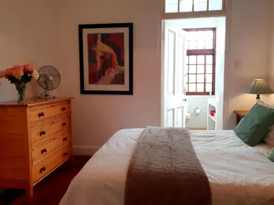 a bedroom with a bed and a dresser with a vase of flowers at Westbank Private Beach Villa, 4 Bedrooms, Private pool, on the Beach! in Gordonʼs Bay
