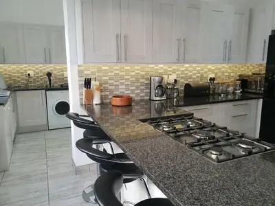 a kitchen with a stove and a counter with stools at Westbank Private Beach Villa, 4 Bedrooms, Private pool, on the Beach! in Gordonʼs Bay