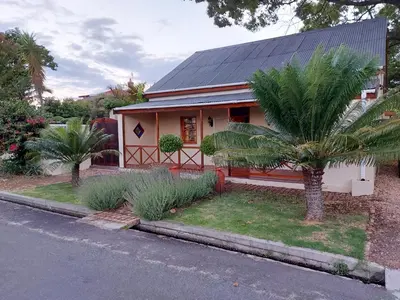 a small house with a palm tree next to a street at Die Heemhuis in Rawsonville