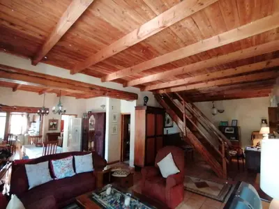 a living room with wooden ceilings and red couches at Die Heemhuis in Rawsonville
