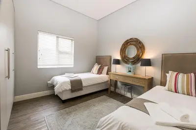 a bedroom with two beds and a mirror at Suburban Bliss Durbanville in Kraaifontein