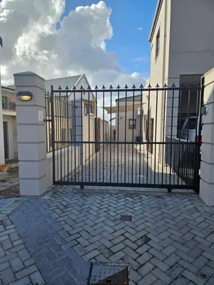 a black wrought iron gate with a brick driveway at Suburban Bliss Durbanville in Kraaifontein