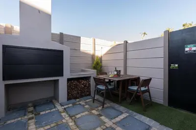a patio with a table and a tv on a wall at Suburban Bliss Durbanville in Kraaifontein