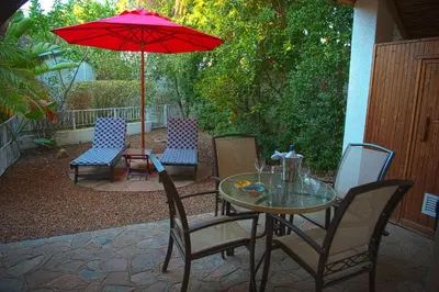 a patio with a table and chairs and an umbrella at Easy Five Guest House in Somerset West