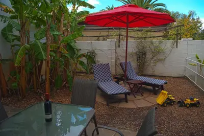a patio with two chairs and a red umbrella at Easy Five Guest House in Somerset West