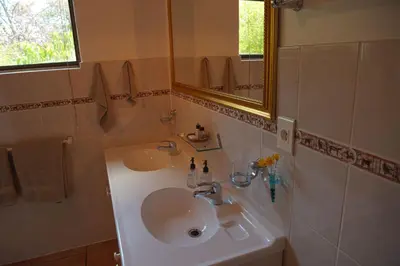 a bathroom with a sink and a mirror at Easy Five Guest House in Somerset West