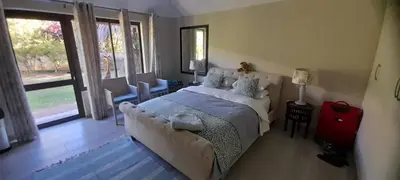 a bedroom with a bed and a red suitcase at Easy Five Guest House in Somerset West
