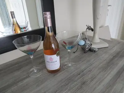 a bottle of wine and two wine glasses on a table at Easy Five Guest House in Somerset West
