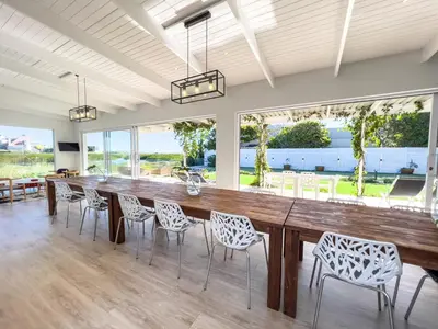 a large dining room with a large wooden table and chairs at Peach on Beach Boutique Guesthouse in Bloubergstrand