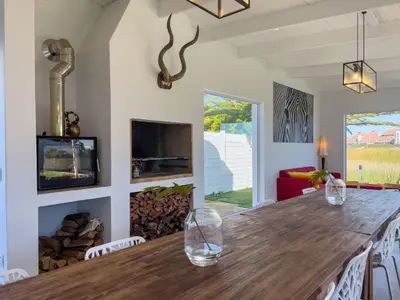 a dining room with a large wooden table and a fireplace at Peach on Beach Boutique Guesthouse in Bloubergstrand