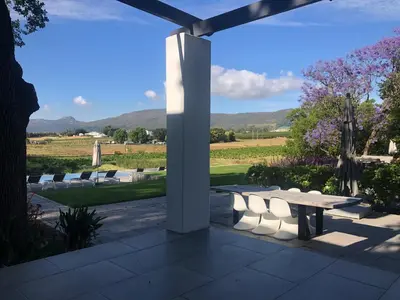 a patio with a table and chairs and a field at Tempel Wines in Paarl