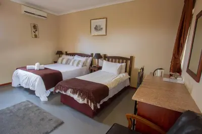 a hotel room with two beds and a table at Ramasibi Guest Services in Panorama