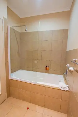 a bathroom with a tub with a glass shower at Ramasibi Guest Services in Panorama
