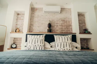 a bedroom with a bed with a brick wall at Les Chambres Guest House in Franschhoek