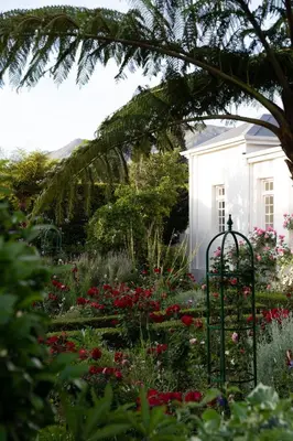 a garden in front of a white house with flowers at Les Chambres Guest House in Franschhoek