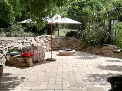 a patio with a table and an umbrella at Leeuwenhof Guesthouse in Caledon