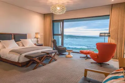 a bedroom with a bed and a large window at Schulphoek Seafront Boutique Hotel in Hermanus