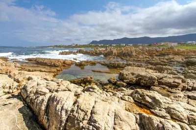 a group of rocks on the ocean with the waves at Schulphoek Seafront Boutique Hotel in Hermanus