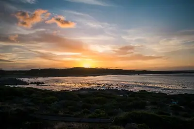 a sunset over a river with the sun setting at Schulphoek Seafront Boutique Hotel in Hermanus