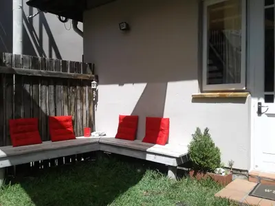 a porch bench with red pillows on a house at The Trailhouse - Betty's Bay in Bettyʼs Bay