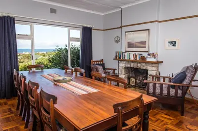 a dining room with a wooden table and a fireplace at The Trailhouse - Betty's Bay in Bettyʼs Bay