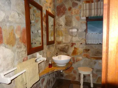 a bathroom with a sink and a stone wall at Braeview Guest House in Hermanus