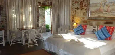 a bedroom with two beds and a table and chairs at Braeview Guest House in Hermanus