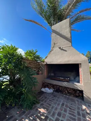 a pizza oven sitting next to a palm tree at Rivers Own Guest Lodge in Breerivier
