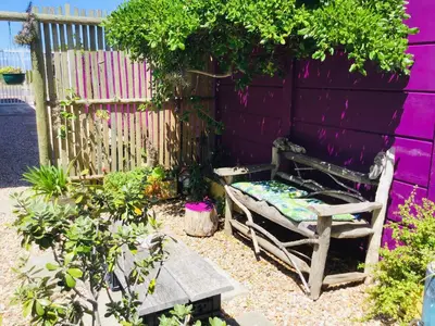 an old bench sitting in front of a purple wall at Funky cottage in Hermanus