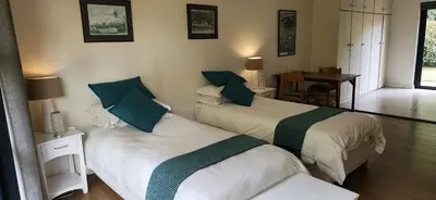 a bedroom with two beds and a table and a desk at Guinea Vine in Stellenbosch