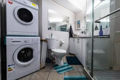 a bathroom with a toilet and a washer and dryer at Blakes Terrace 903 in Strand
